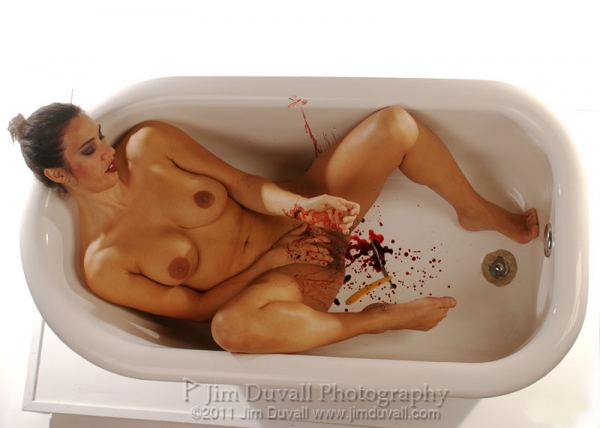 nude woman with razor and cut writs in a white tub